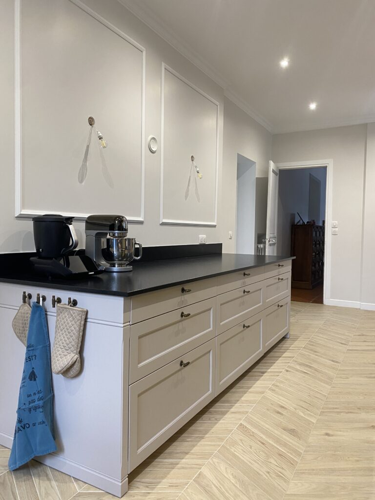 Cuisine dans un style classique beige cachemire. Plan de travail granite noir. Piano de cuisson Lacanche. Bouton de porte laiton vieilli