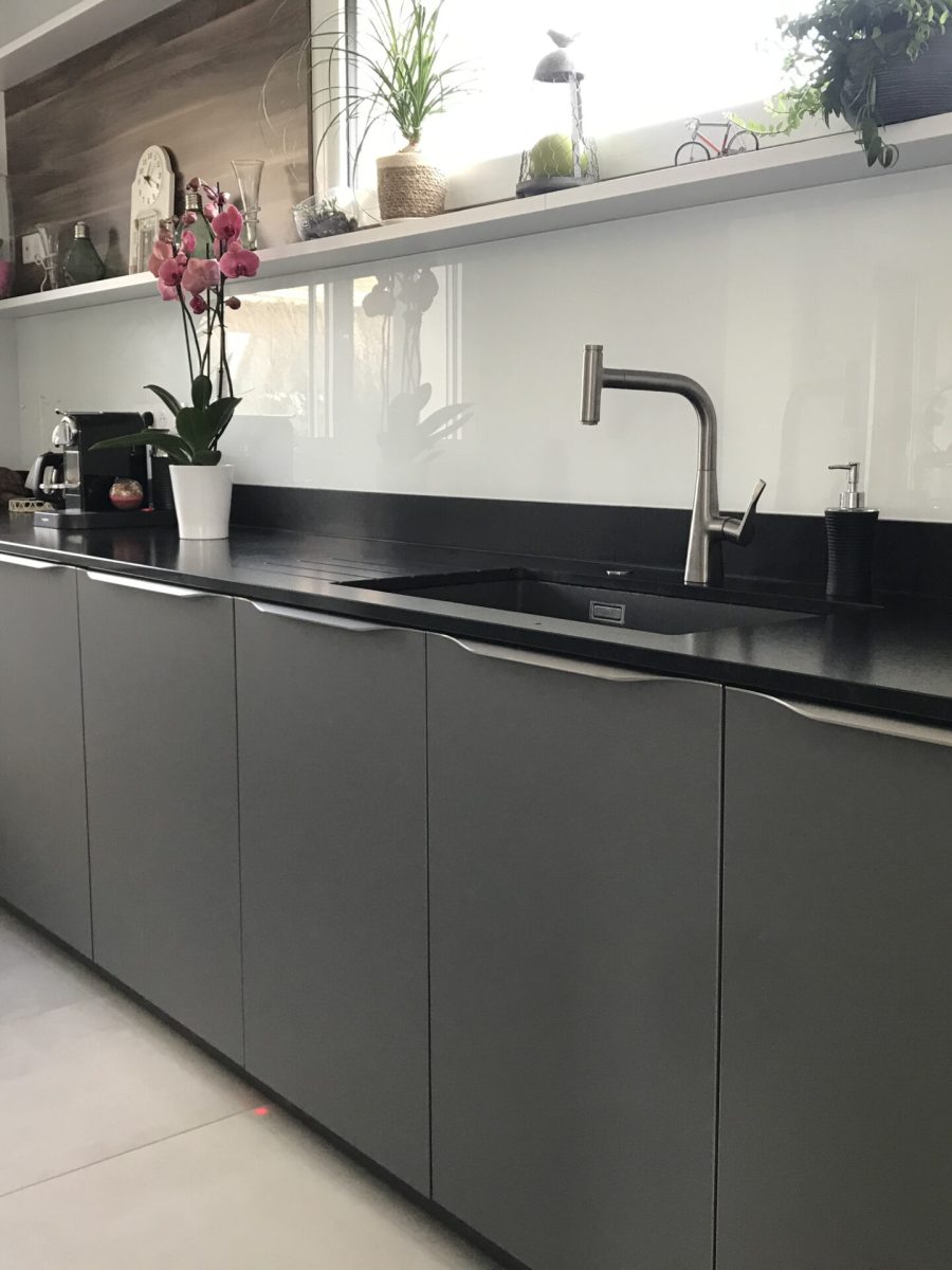 linéaire façade gris foncé avec plan de travail en granit noir, trois colonnes blanche mat et niche en bois foncé sur le mur - Conception de la cuisine et pose par Concept Art Cuisine